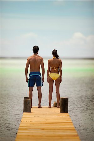 simsearch:6128-08798831,k - Young couple look out at the ocean while standing on a pier. Fotografie stock - Premium Royalty-Free, Codice: 6128-08798808