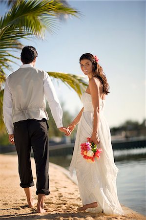 simsearch:6128-08798792,k - Happy young newlywed couple walking along a beach after their wedding. Fotografie stock - Premium Royalty-Free, Codice: 6128-08798831