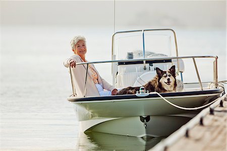 simsearch:6128-08798919,k - Smiling mature woman relaxes on a boat with her big fluffy dog. Photographie de stock - Premium Libres de Droits, Code: 6128-08798923