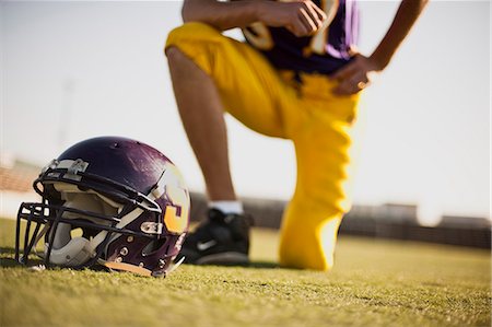 simsearch:625-02931241,k - Football helmet with player kneeling in background. Fotografie stock - Premium Royalty-Free, Codice: 6128-08799093