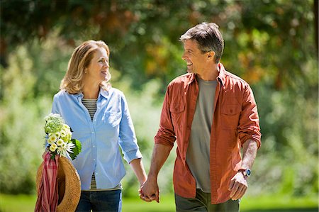 Happy middle aged couple walking hand in hand through a green park. Stock Photo - Premium Royalty-Free, Code: 6128-08799008