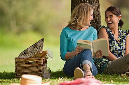 simsearch:6128-08727583,k - Happy friends reading a book together under a tree at the park. Stock Photo - Premium Royalty-Free, Code: 6128-08799029