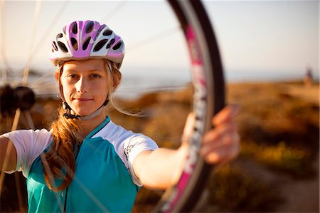 simsearch:6128-08738600,k - Portrait of a female cyclist holding up a cycle wheel. Stock Photo - Premium Royalty-Free, Code: 6128-08799141