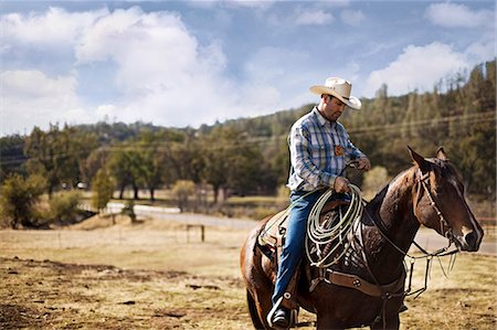 simsearch:6128-08738561,k - Cowboy with lasso riding horseback on a ranch Stock Photo - Premium Royalty-Free, Code: 6128-08799115