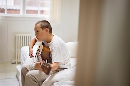 simsearch:6128-08728230,k - Boy playing an acoustic guitar in a bedroom. Fotografie stock - Premium Royalty-Free, Codice: 6128-08727446