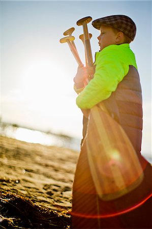 simsearch:6128-08728334,k - Young boy carrying an armful of oars along the beach at sunset after a long day canoeing. Stock Photo - Premium Royalty-Free, Code: 6128-08727461