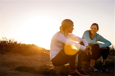 simsearch:6128-08738600,k - Two young women take a break from their sunrise jog along the cliffs to sit and have a cheerful discussion. Stock Photo - Premium Royalty-Free, Code: 6128-08727468