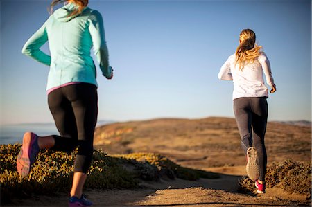 simsearch:6128-08727475,k - Two young women go for a sunrise jog together along the cliff tops by the ocean. Photographie de stock - Premium Libres de Droits, Code: 6128-08727471