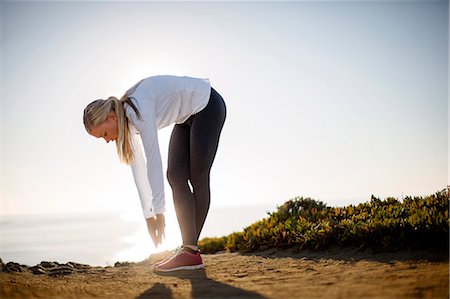 simsearch:6128-08727475,k - Young woman takes a break from her jog along the cliffs to stretch in the sunrise light. Photographie de stock - Premium Libres de Droits, Code: 6128-08727477