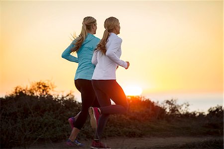 simsearch:6128-08738599,k - Two young women go for a sunrise jog together along the cliff tops by the ocean. Foto de stock - Royalty Free Premium, Número: 6128-08727478