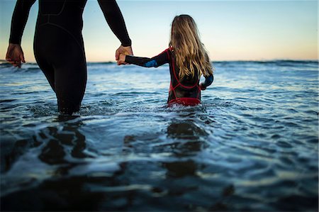 pictures of girls at beach rear - Young girl holds her father's hand as they wade into the ocean together. Stock Photo - Premium Royalty-Free, Code: 6128-08727485