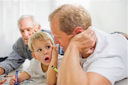 senior child listen - Young boy with his mid-adult father and mature grandfather lying on the floor coloring in. Stock Photo - Premium Royalty-Free, Code: 6128-08727419