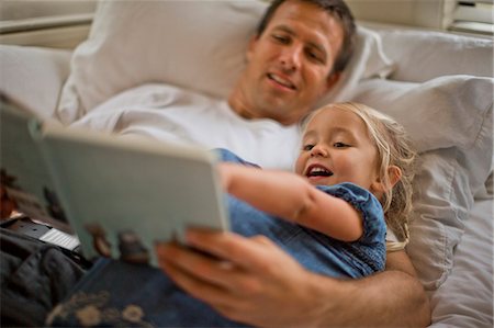 simsearch:6128-08727525,k - Father lying down reading a book with his daughter. Stock Photo - Premium Royalty-Free, Code: 6128-08727513