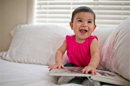 Laughing baby holding a picture book. Stock Photo - Premium Royalty-Free, Code: 6128-08727523