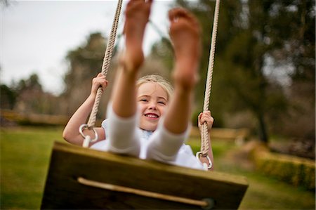 simsearch:6128-08727525,k - Happy young girl swinging on a wooden rope swing. Stock Photo - Premium Royalty-Free, Code: 6128-08727530