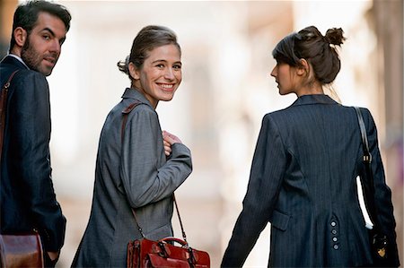 simsearch:693-03307851,k - Portrait of a smiling young businesswoman walking with her colleagues. Photographie de stock - Premium Libres de Droits, Code: 6128-08727670