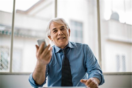 senior executive meeting - Happy businessman using a smartphone during a business meeting. Stock Photo - Premium Royalty-Free, Code: 6128-08727693