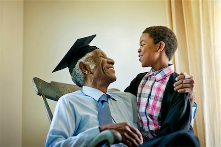 senior - Senior man wearing a mortarboard, sitting in a rocking chair with his grandson. Photographie de stock - Premium Libres de Droits, Code: 6128-08727733