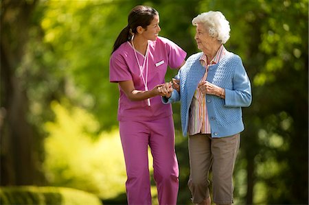 simsearch:6128-08728035,k - Happy young nurse helpfully assisting an elderly patient to walk outside. Foto de stock - Sin royalties Premium, Código: 6128-08727839