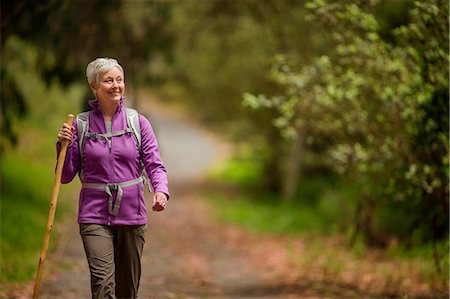 Happy mature woman enjoys a peaceful hike through the woods. Foto de stock - Royalty Free Premium, Número: 6128-08727976