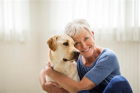 Smiling mature woman hugging her dog. Stock Photo - Premium Royalty-Free, Code: 6128-08727996