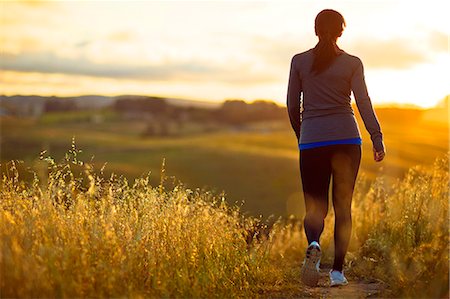 simsearch:6128-08738599,k - Energetic young woman jogging through the rural countryside at sunset. Foto de stock - Royalty Free Premium, Número: 6128-08727905