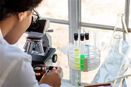 simsearch:6105-05396464,k - Scientist looking through a microscope at a sample. Foto de stock - Sin royalties Premium, Código: 6128-08728045