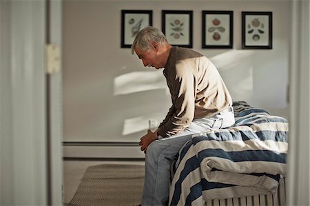 simsearch:614-07487219,k - Depressed senior man sitting alone on a bed. Fotografie stock - Premium Royalty-Free, Codice: 6128-08728078