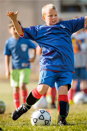 simsearch:6128-08766894,k - Young boy kicking a ball during a soccer game. Foto de stock - Sin royalties Premium, Código: 6128-08728082