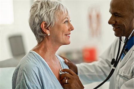 simsearch:6128-08766918,k - Cheerful mature woman gets her heartbeat checked by a friendly doctor. Foto de stock - Royalty Free Premium, Número: 6128-08728011