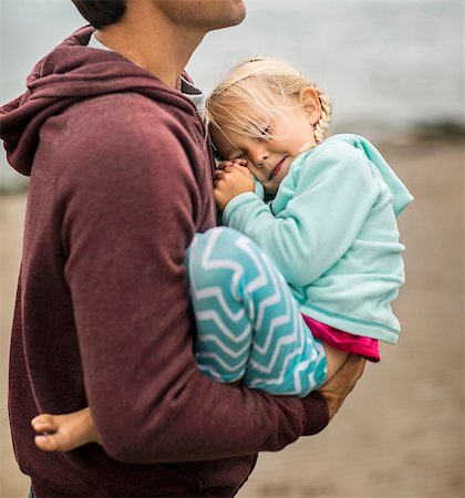 simsearch:6128-08728311,k - Young blond girl snuggles into her father's chest at the beach. Photographie de stock - Premium Libres de Droits, Code: 6128-08728024