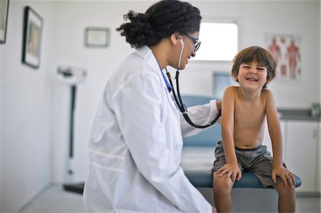 simsearch:6128-08728035,k - Doctor listening to a young boy's heartbeat with a stethoscope. Foto de stock - Sin royalties Premium, Código: 6128-08728035