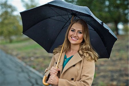 simsearch:6128-08727668,k - Portrait of a young woman holding an umbrella in the rain. Stock Photo - Premium Royalty-Free, Code: 6128-08728176