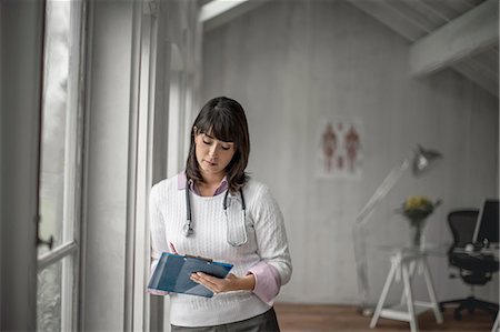 simsearch:6128-08780904,k - Doctor writing on a file in her office. Photographie de stock - Premium Libres de Droits, Code: 6128-08728199