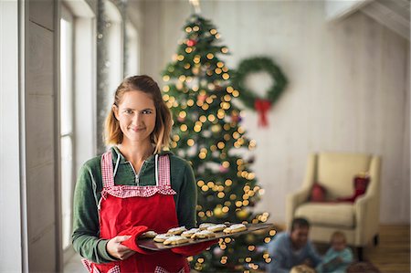 fairy lights - Portrait of a smiling woman holding a tray of freshly baked Christmas cookies. Stock Photo - Premium Royalty-Free, Code: 6128-08728290