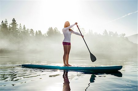paddle - Active young woman paddleboarding across a lake. Stock Photo - Premium Royalty-Free, Code: 6128-08728348