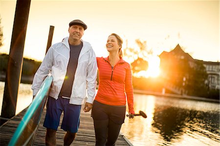 simsearch:6128-08728347,k - Happy paddleboarding couple walking along a pier at sunset. Stock Photo - Premium Royalty-Free, Code: 6128-08728316