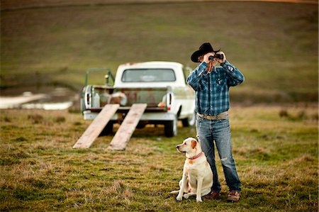 simsearch:400-03944669,k - Farmer looking through binoculars on a paddock with his dog by his side. Photographie de stock - Premium Libres de Droits, Code: 6128-08737553