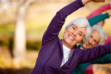 sports old woman - Portrait of a smiling senior woman stretching with her arms above her head in a park with her friends. Stock Photo - Premium Royalty-Free, Code: 6128-08737564