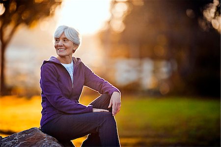 Smiling senior woman sitting on a rock in a park. Foto de stock - Sin royalties Premium, Código: 6128-08737580