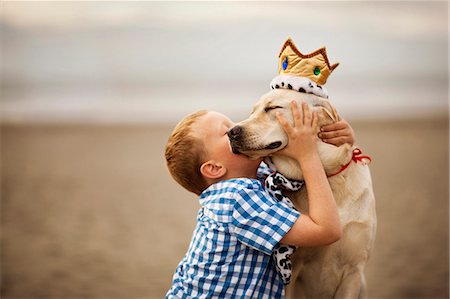 simsearch:600-06531469,k - Small boy hugging and kissing his dog at the beach. Photographie de stock - Premium Libres de Droits, Code: 6128-08737586