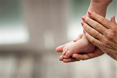 foot compare - Close-up of elderly woman's hands as she holds her baby grandson's foot. Foto de stock - Sin royalties Premium, Código: 6128-08737597