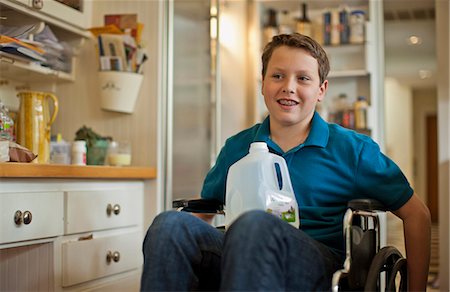 person in wheelchair at home - Teenage boy sitting in a wheelchair with a plastic bottle of milk. Foto de stock - Sin royalties Premium, Código: 6128-08737680