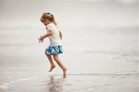 simsearch:6128-08747866,k - Happy young girl playing in shallow water on a beach. Foto de stock - Sin royalties Premium, Código: 6128-08737696