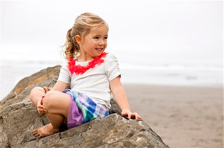 simsearch:6128-08747842,k - Smiling young girl sitting on a rock on a beach. Stockbilder - Premium RF Lizenzfrei, Bildnummer: 6128-08737699