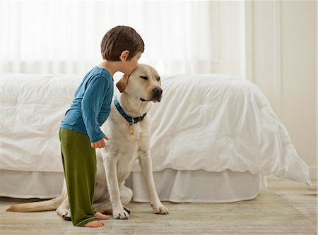 Young boy playing with his dog in a bedroom. Stock Photo - Premium Royalty-Free, Code: 6128-08737783