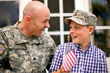 exército - Smiling young boy and his father sitting on the porch of their home. Foto de stock - Royalty Free Premium, Número: 6128-08737842