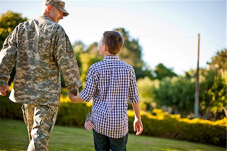 simsearch:6128-08737856,k - Male soldier holding hands with his son in their back yard. Photographie de stock - Premium Libres de Droits, Code: 6128-08737858