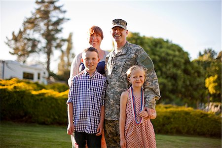 Portrait of a smiling male soldier standing with his family in the back yard of their home. Stock Photo - Premium Royalty-Free, Code: 6128-08737863