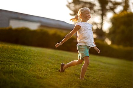 Young girl skipping across a green lawn. Stock Photo - Premium Royalty-Free, Code: 6128-08737883